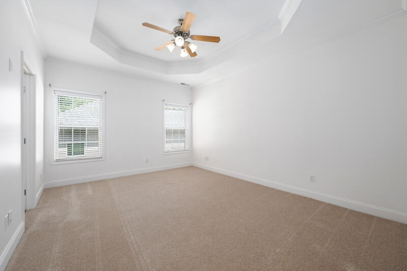 Primary bedroom with a tray ceiling and carpet
